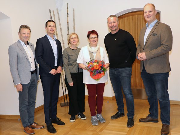 Die neue Schuldirektorin Heidrun Achleitner mit Blumenstrauß umringt von fünf Vertretern von Stadt und Bildungsdirektion